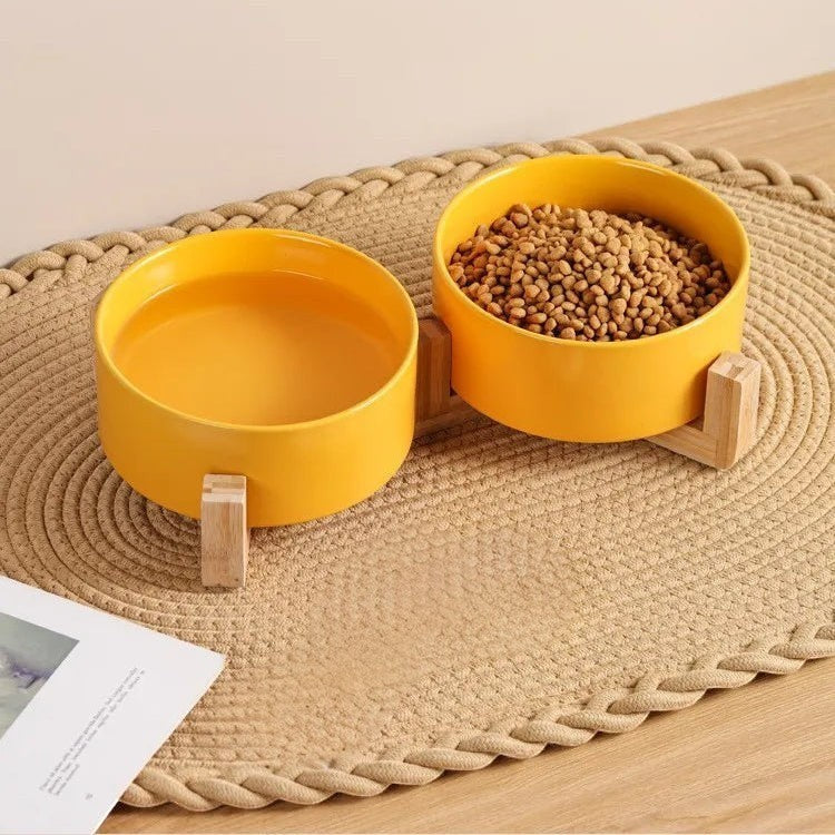 Jeu de deux gamelles Bofélin jaunes en céramique sur supports en bois naturel pour chat sur un tapis tressé